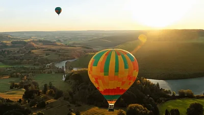 Colorful Hot Air Balloons Floating Over Scenic Valley Landscape
