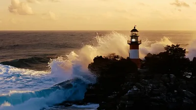 Lighthouse Standing On Rocky Coastline During Sunset
