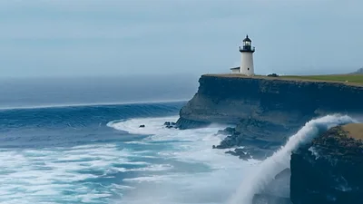Powerful Ocean Waves Crashing Against Coastal Lighthouse Cliffs