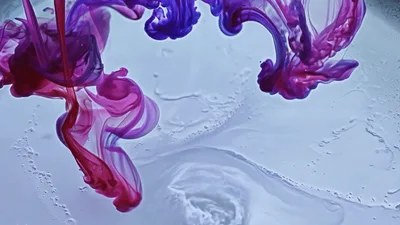 Purple And Pink Ink Droplets Diffusing In Clear Water