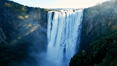 Aerial View Of Majestic Waterfall Cascading Down Rocky Cliffs