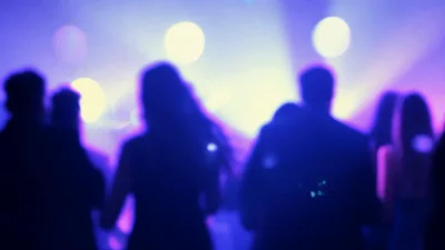 Silhouetted Crowd Dancing At A Nightclub Under Colorful Lights
