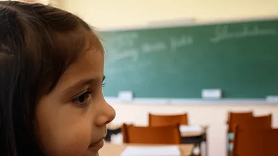 Young Girl Looking At Classroom Chalkboard
