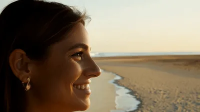 Smiling Woman Enjoying Sunset On A Sandy Beach