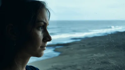 Pensive Woman Looking Out Window At The Ocean