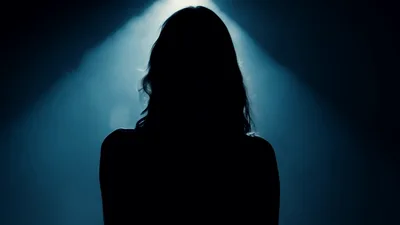 Silhouette Of A Woman Emerging From Darkness Into Spotlight