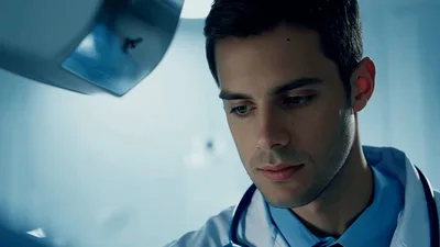 Young Male Doctor Examining Patient In Hospital Room