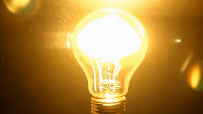 Glowing Incandescent Light Bulb With Floating Dust Particles