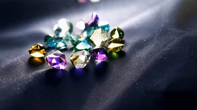 Colorful Gemstones Falling Onto Dark Silk Fabric