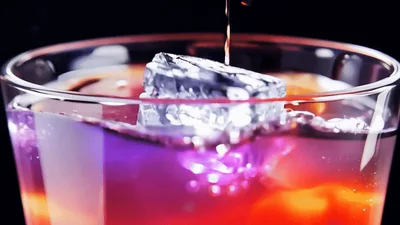 Ice Cube Dropping Into A Glass Of Red Drink