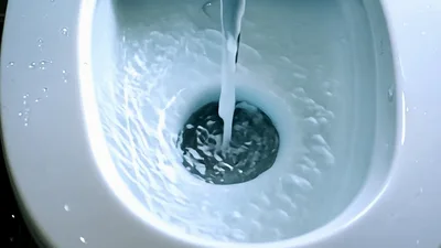 Water Pouring Into A White Ceramic Toilet Bowl