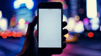 Hand Holding Smartphone With Blank Screen In City