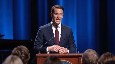 Man In Suit Giving A Speech At A Podium