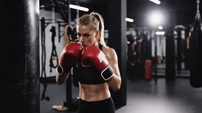 Fit Woman Boxing Heavy Bag In Gym