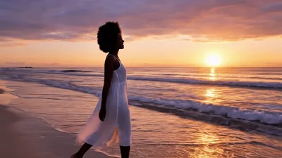 Black Woman Walking Along Tropical Beach At Sunset