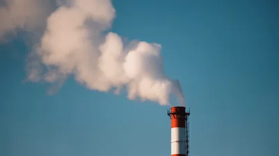 Industrial Chimney Emitting Thick White Smoke Into Blue Sky
