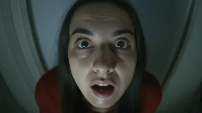 Woman Looking Through Door Peephole With Shocked Expression