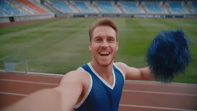 Male Athlete Holding Blue Pom Poms In Stadium