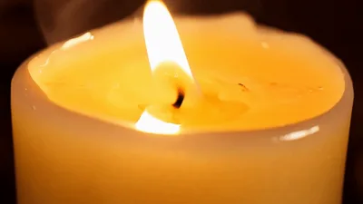 Close Up Of A Burning White Pillar Candle