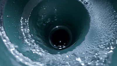 Water Swirling Down A Green Drain Pipe