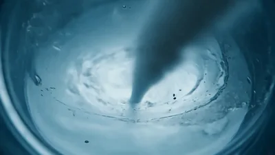 White Liquid Pouring Into Clear Water Creating Vortex