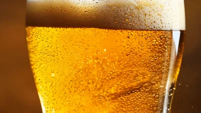 Golden Beer Pouring Into A Glass With Condensation