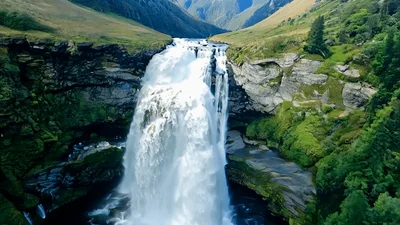 Aerial View Of Powerful Waterfall Cascading Down Rocky Cliff