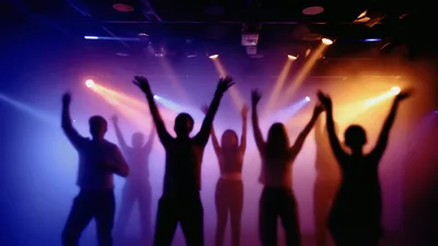 Silhouetted People Dancing Under Colorful Stage Lights
