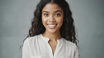 Young Woman Smiling At Camera Against Grey Background