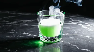 Green Liquid Filling A Glass With Rising Smoke
