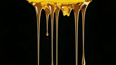 Golden Honey Or Oil Dripping Down Against Black Background