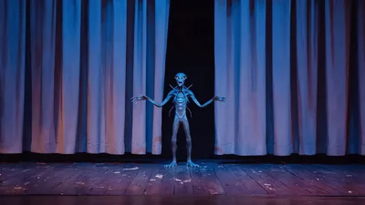 Alien Creature Standing On A Dark Theater Stage