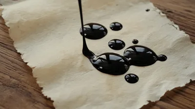 Black Ink Dripping Onto Aged Parchment Paper