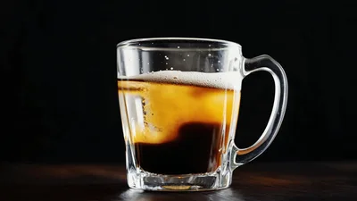 Cream Swirling Into Iced Coffee In Glass Mug