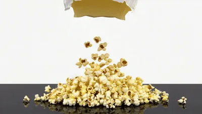 Popcorn Pouring From A Bag Onto A Reflective Surface