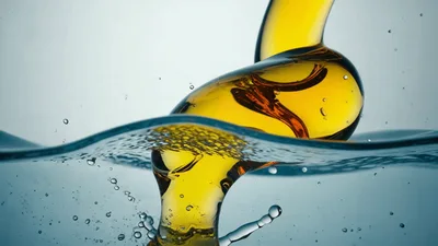 Golden Oil Pouring Into Clear Water Surface