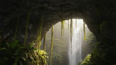 Waterfall Cascading Through A Lush Tropical Cave Opening