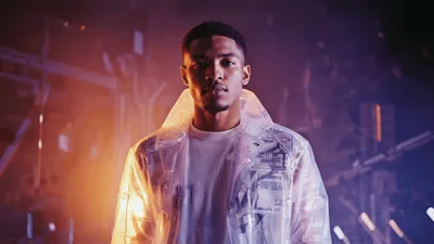 Young Man Wearing Transparent Raincoat Standing In Studio