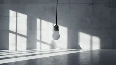 Hanging Light Bulb Swinging In Minimalist Concrete Room