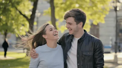 Happy Young Couple Walking And Laughing In Park