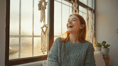 Happy Young Woman Laughing By A Sunny Window
