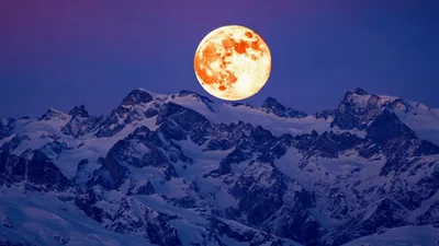 Full Moon Rising Over Snowy Mountain Peaks