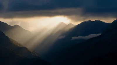 Sunlight Beams Piercing Through Dark Mountain Clouds