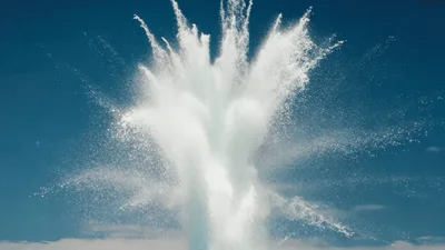 Powerful Water Geyser Erupting Against Clear Blue Sky