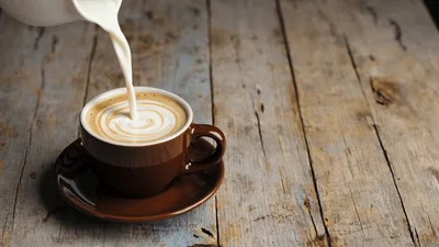 Pouring Steamed Milk Into A Brown Coffee Cup