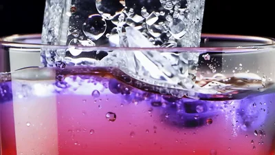 Ice Cube Dropping Into A Glass Of Colorful Liquid
