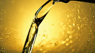 Golden Liquid Pouring From Bottle Into Glass