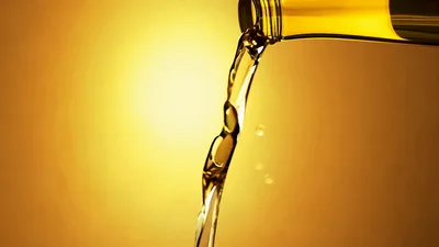 Golden Liquid Pouring From Glass Bottle