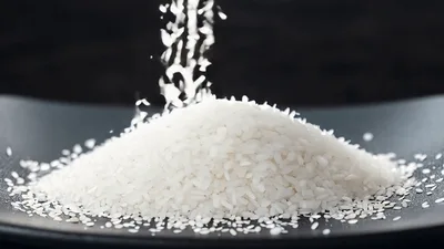 White Rice Grains Pouring Onto A Black Plate