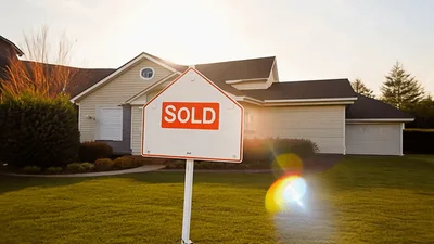 Sold Real Estate Sign In Front Of Suburban House